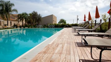 Una piscina al aire libre de temporada, sillones reclinables de piscina