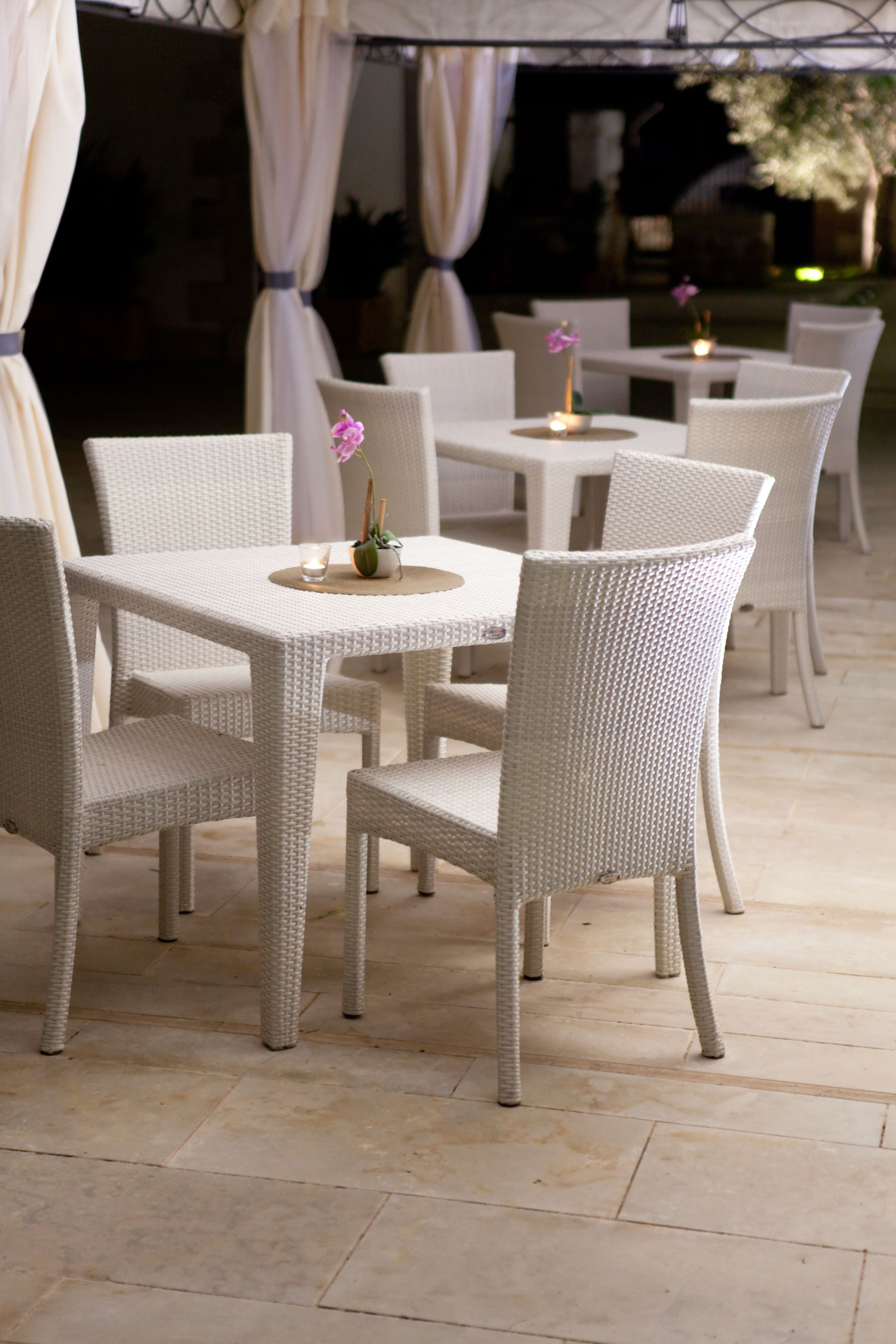 A dining area with wicker furniture and a tiled floor.