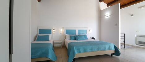 A bedroom with two beds, white walls, and a wooden ceiling.