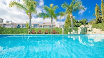 Alberca al aire libre, sombrillas en la alberca y camastros