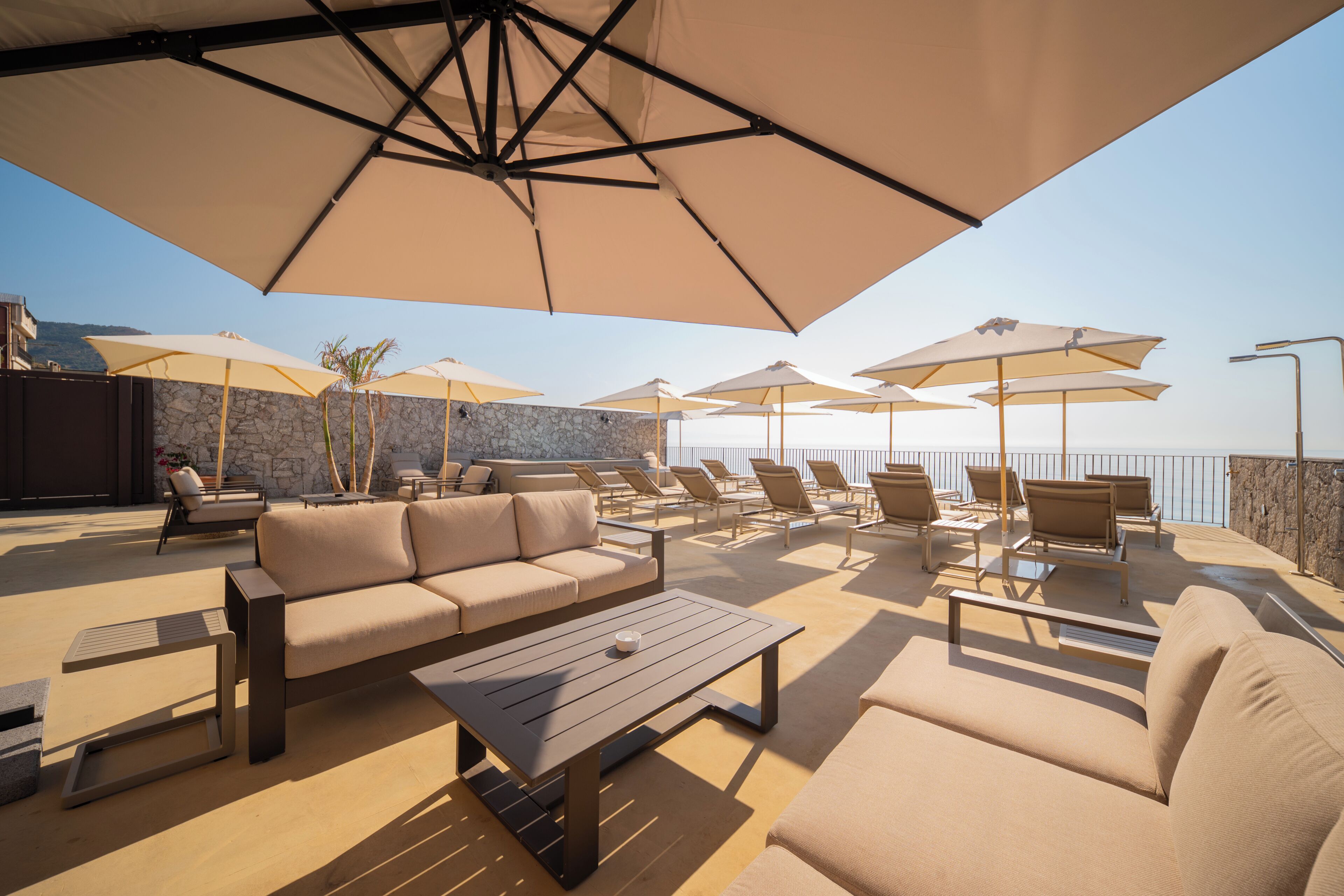 A rooftop terrace with outdoor seating, including sofas and chairs, under large umbrellas.