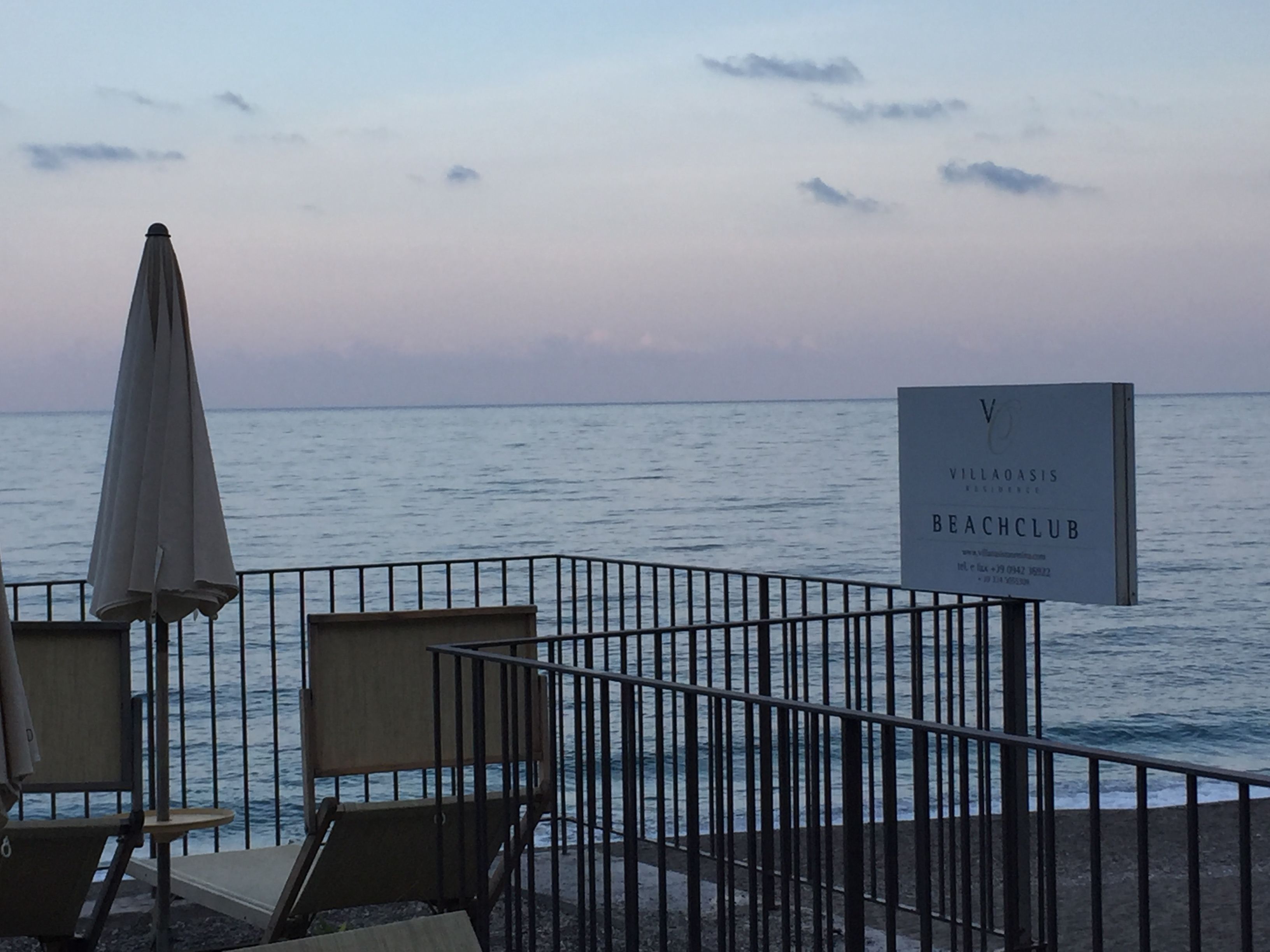 Un espacio de descanso frente a la playa, con un letrero que indica Club de Playa Oasis Villa.