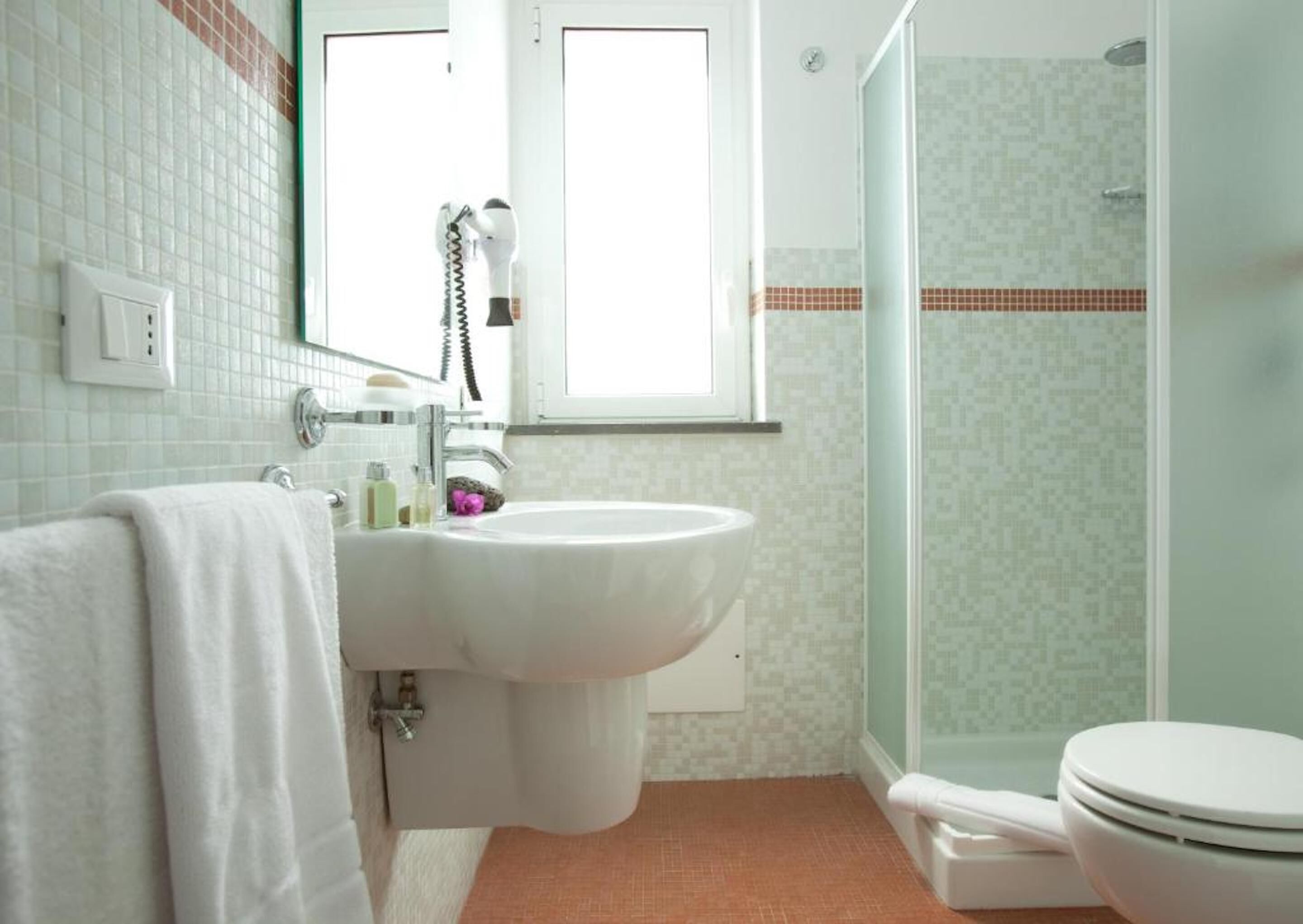 Ein Badezimmer mit Waschbecken, Spiegel, Handtuch, Dusche und Toilette.
