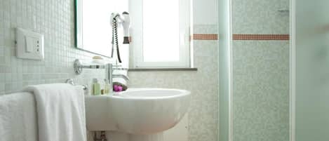 Ein Badezimmer mit Waschbecken, Spiegel, Handtuch, Dusche und Toilette.