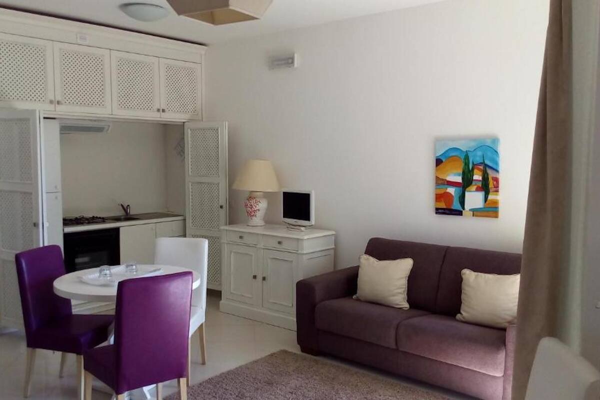 A compact living space with a dining area, kitchenette, and a sofa.