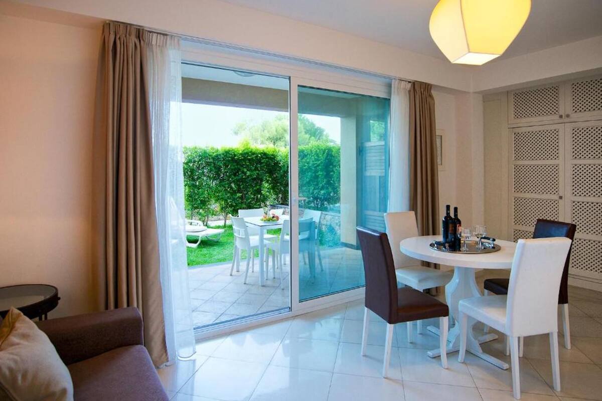 A modern room with a sliding glass door leading to a patio, a dining table with chairs, and a sofa.
