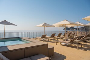 A poolside area with lounge chairs and umbrellas, overlooking a body of water. - Villa Oasis Residence (Taormina)
