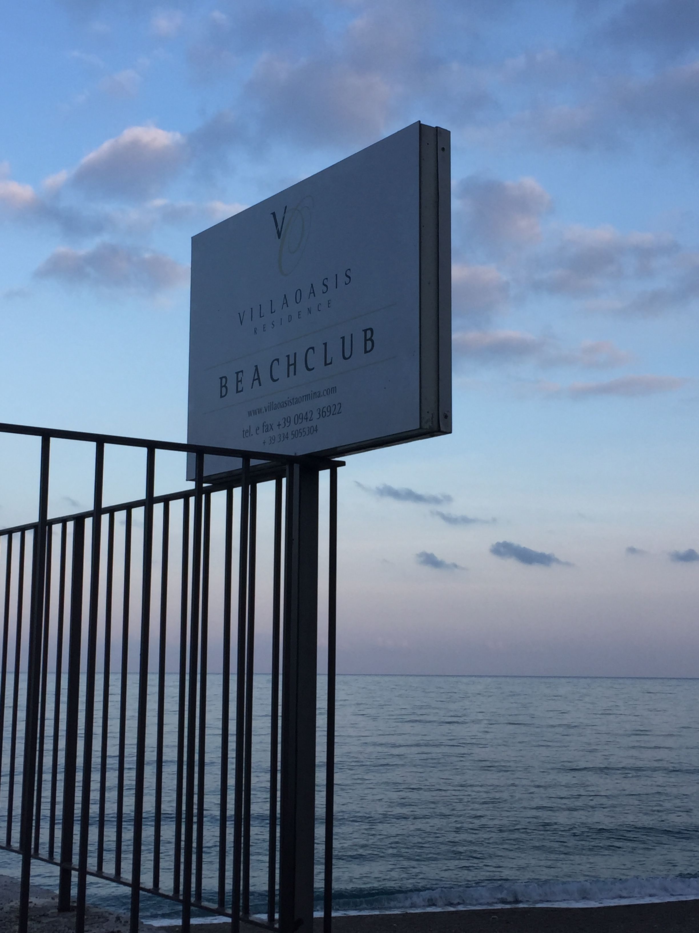 Senyal de platja per a Villa Oasis Beach Club amb informació de contacte.