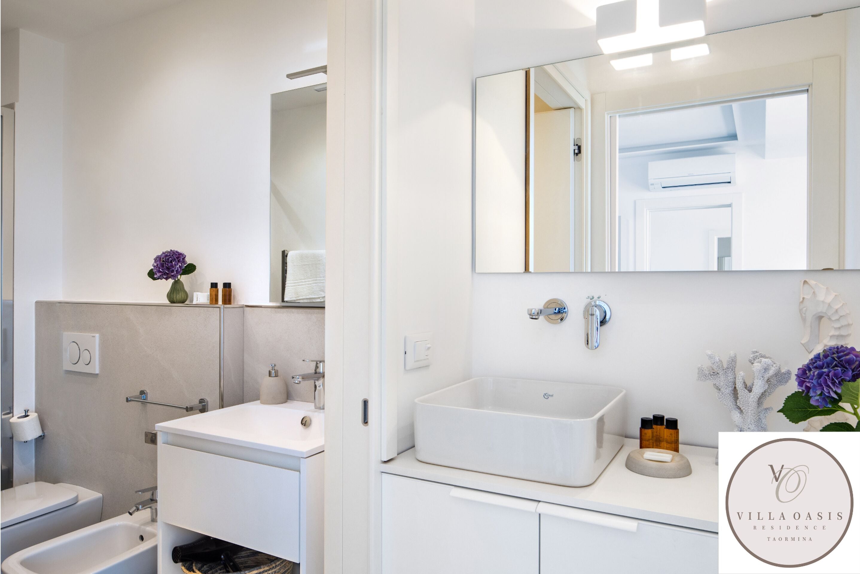 Een moderne badkamer met een wit wastafelmeubel, een grote spiegel en een toilet.