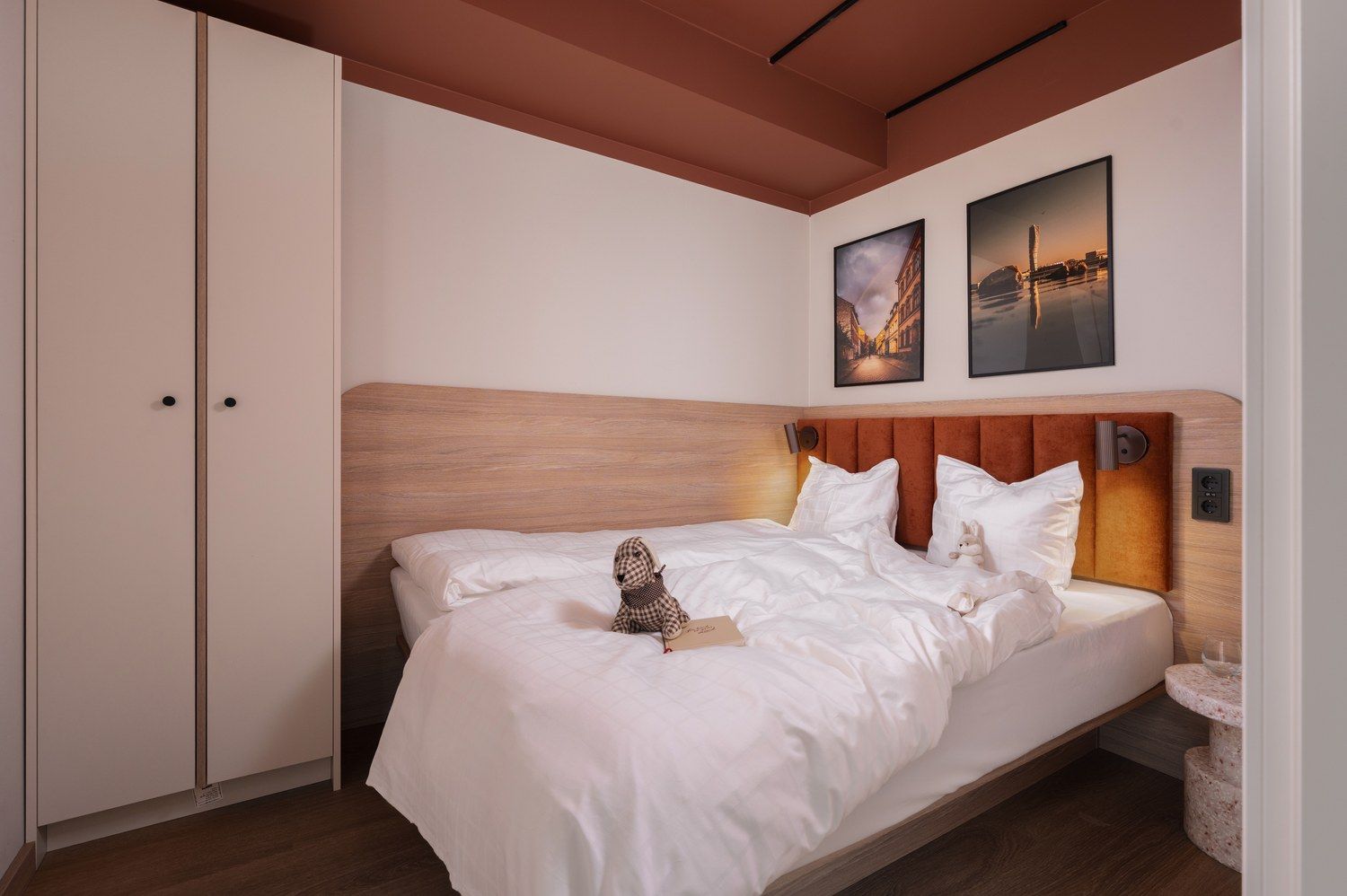 Una habitación de hotel con una cama grande, un cabecero de madera, un armario y dos cuadros en la pared.