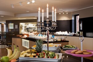 Zona de buffet con diferentes opciones de comida, un candelabro y una cocina al fondo.