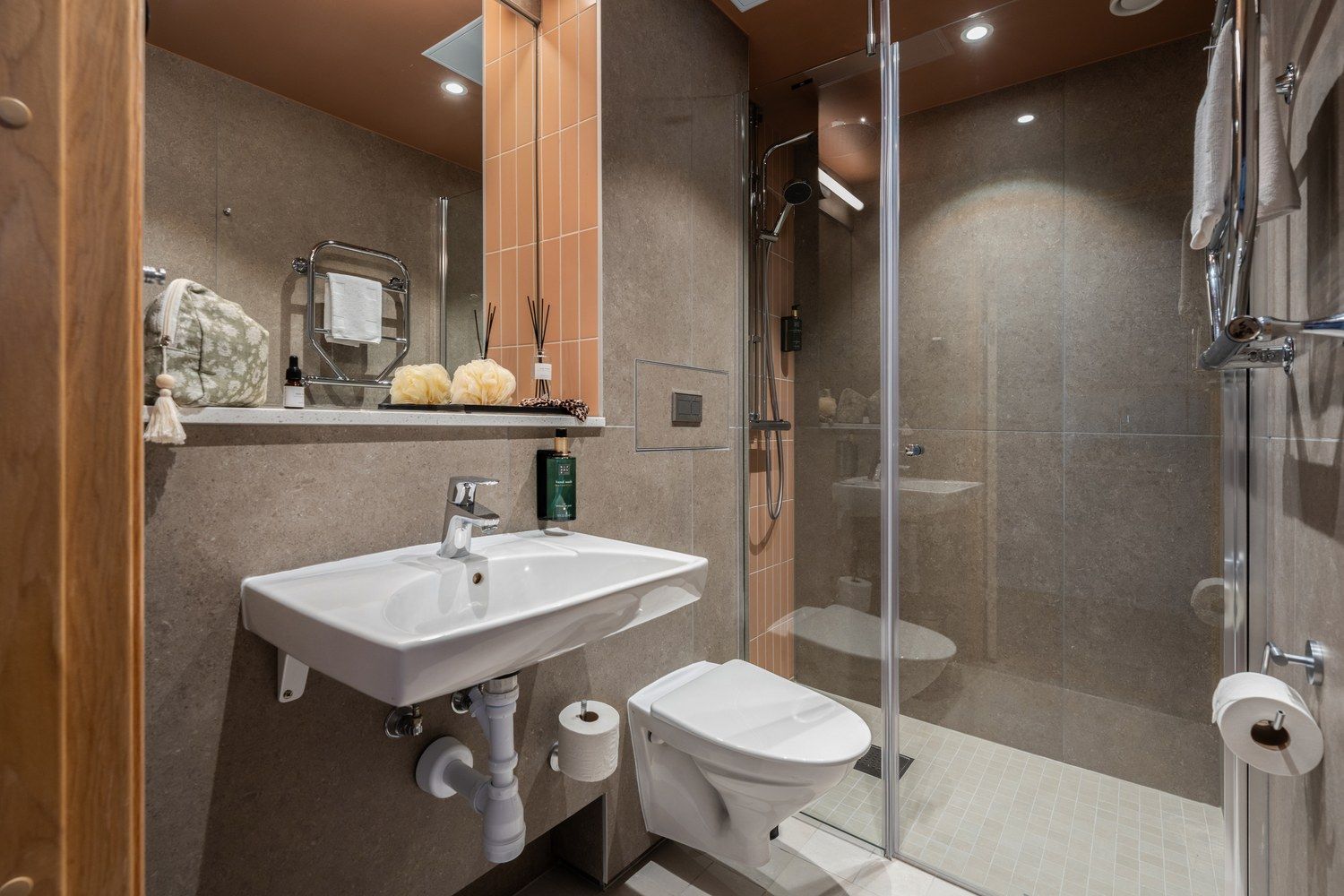 Un baño moderno con ducha envuelta en cristal, un lavabo blanco y un inodoro.