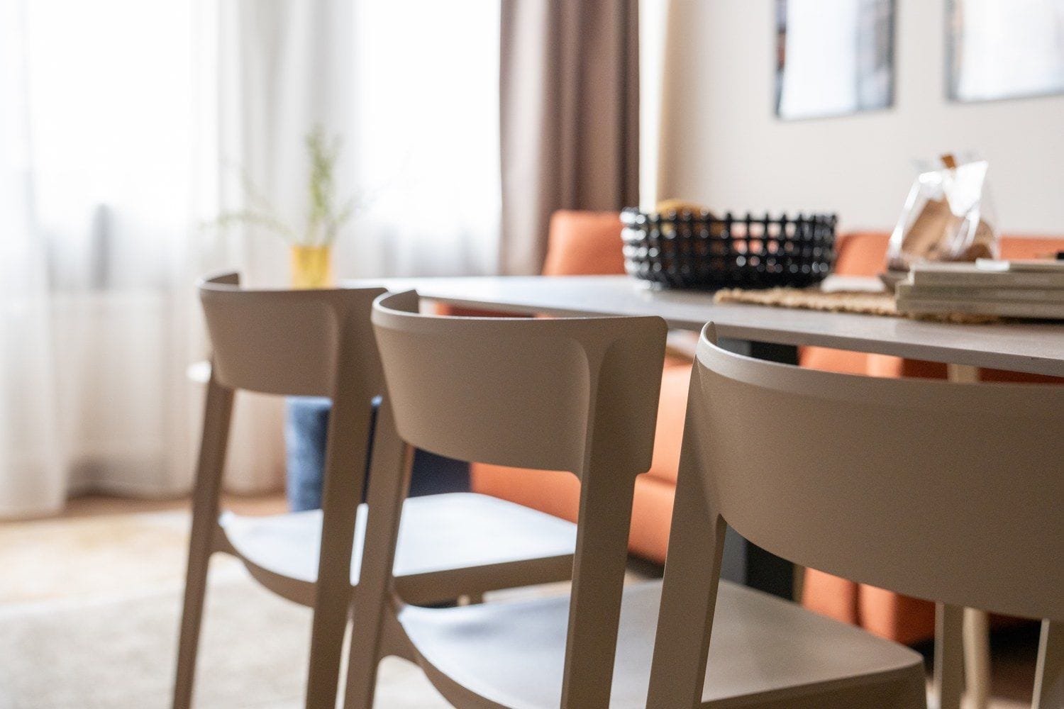 Un comedor con una mesa redonda y dos sillas, una planta y una ventana con cortinas.