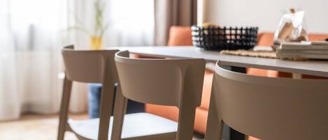 Un comedor con una mesa redonda y dos sillas, una planta y una ventana con cortinas.
