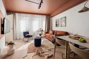 A modern living room with a sofa, a dining table, and a television. - Sky Hotel Malmö City (Malmö)
