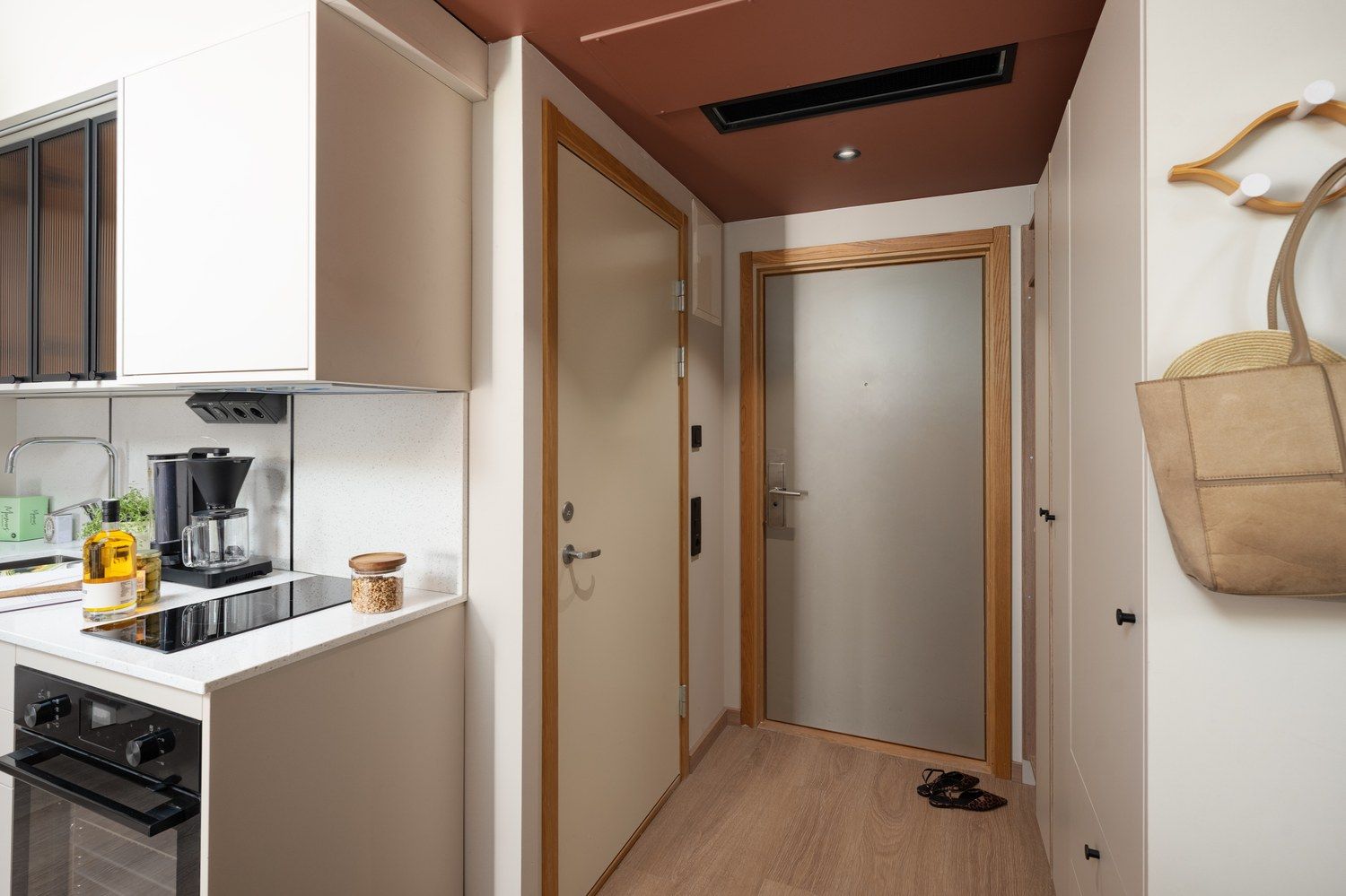 A compact kitchen with a stove, coffee maker, and a hanging bag.