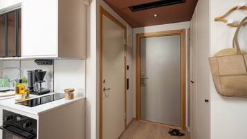 A compact kitchen with a stove, coffee maker, and a hanging bag.