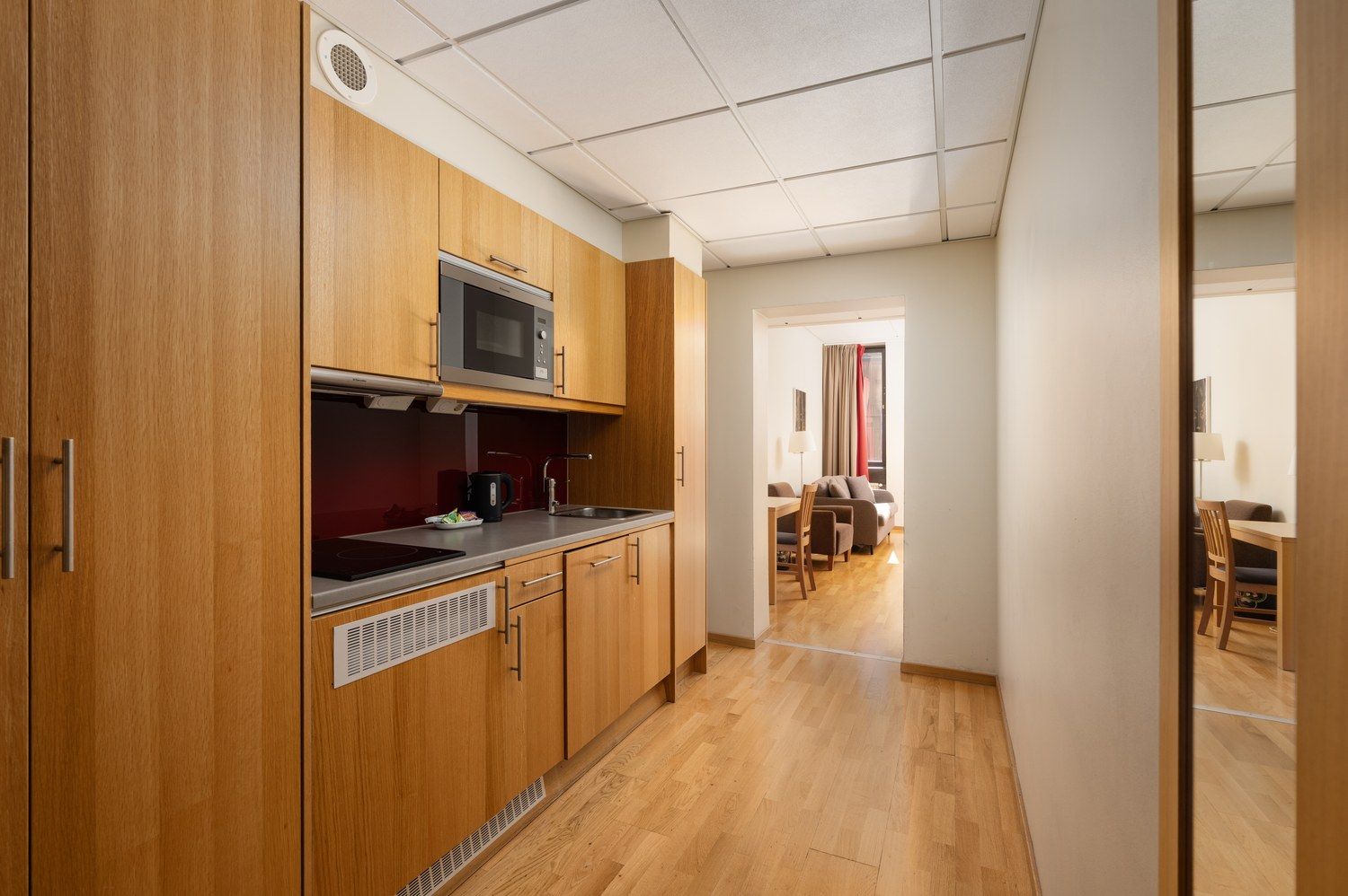 A compact kitchen with wooden cabinets, a microwave, and a sink.