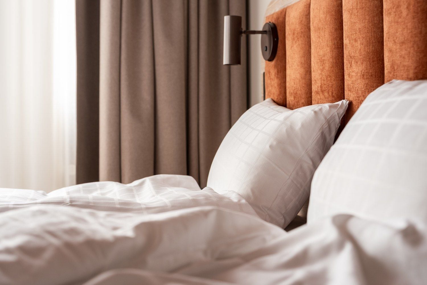 A bed with white bedding and a headboard with a wooden panel.