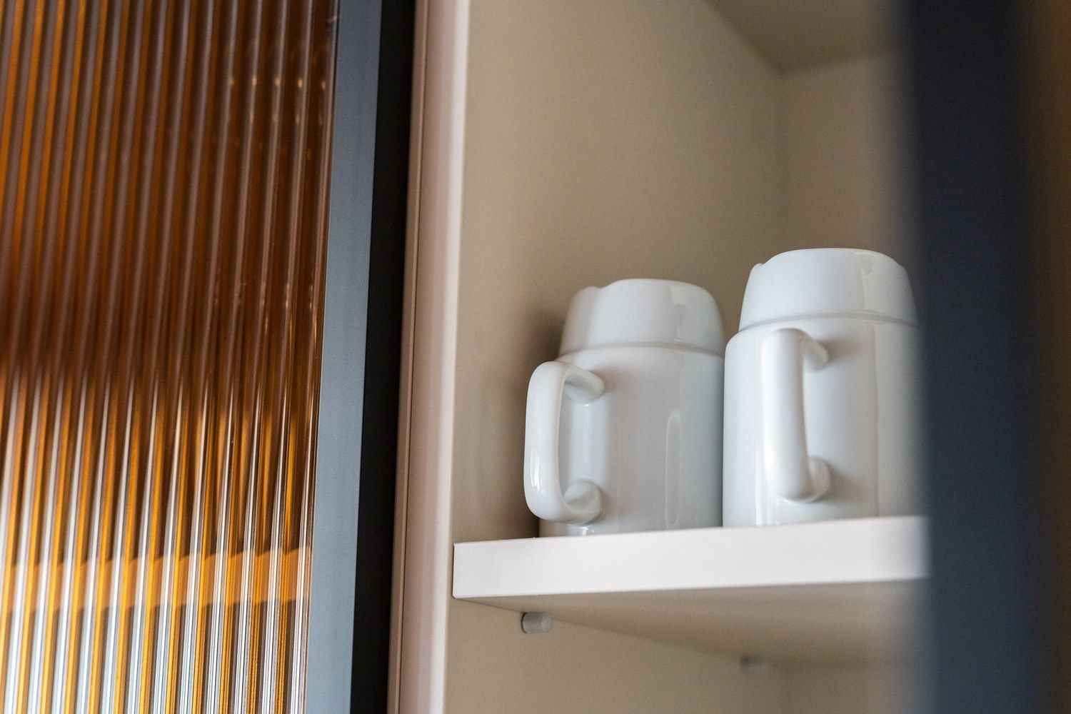 Un estante blanco con dos tazas blancas.