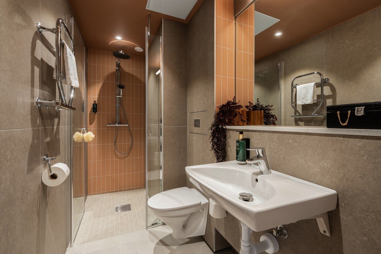 A modern bathroom with a glass-enclosed shower, a white toilet, and a sink with a mirror above it.
