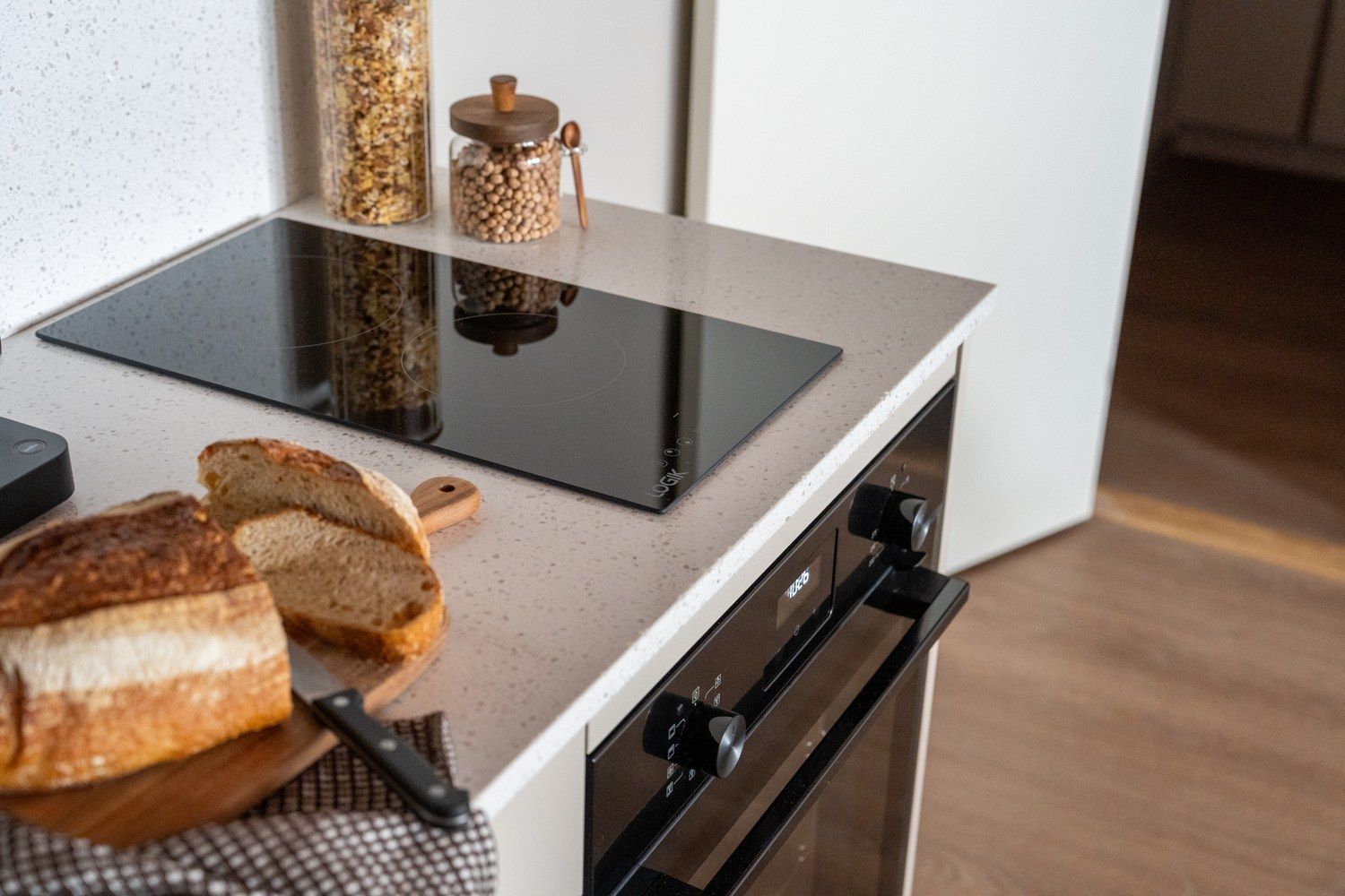 A kitchen with a countertop, a bread loaf, a knife, and a spice jar.