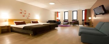 Habitación de hotel con dos camas, un sofá, una televisión y un escritorio.