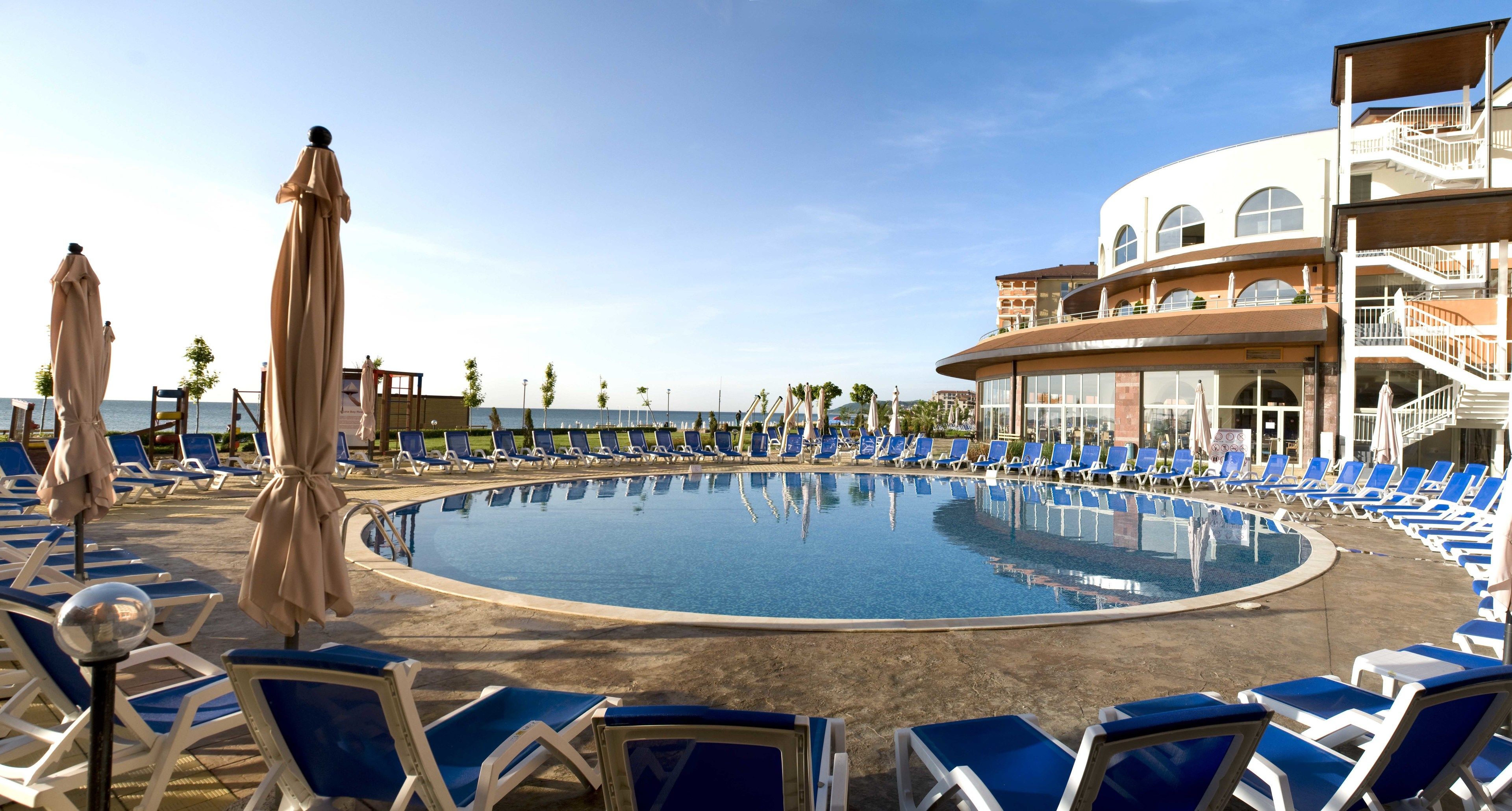 Alberca techada, alberca al aire libre y sombrillas en la alberca