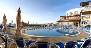 Una piscina techada, una piscina al aire libre, sombrillas