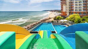 A water slide at a beachside hotel with a view of the ocean and a building with multiple balconies. - Sol Luna Bay Resort (Byala)