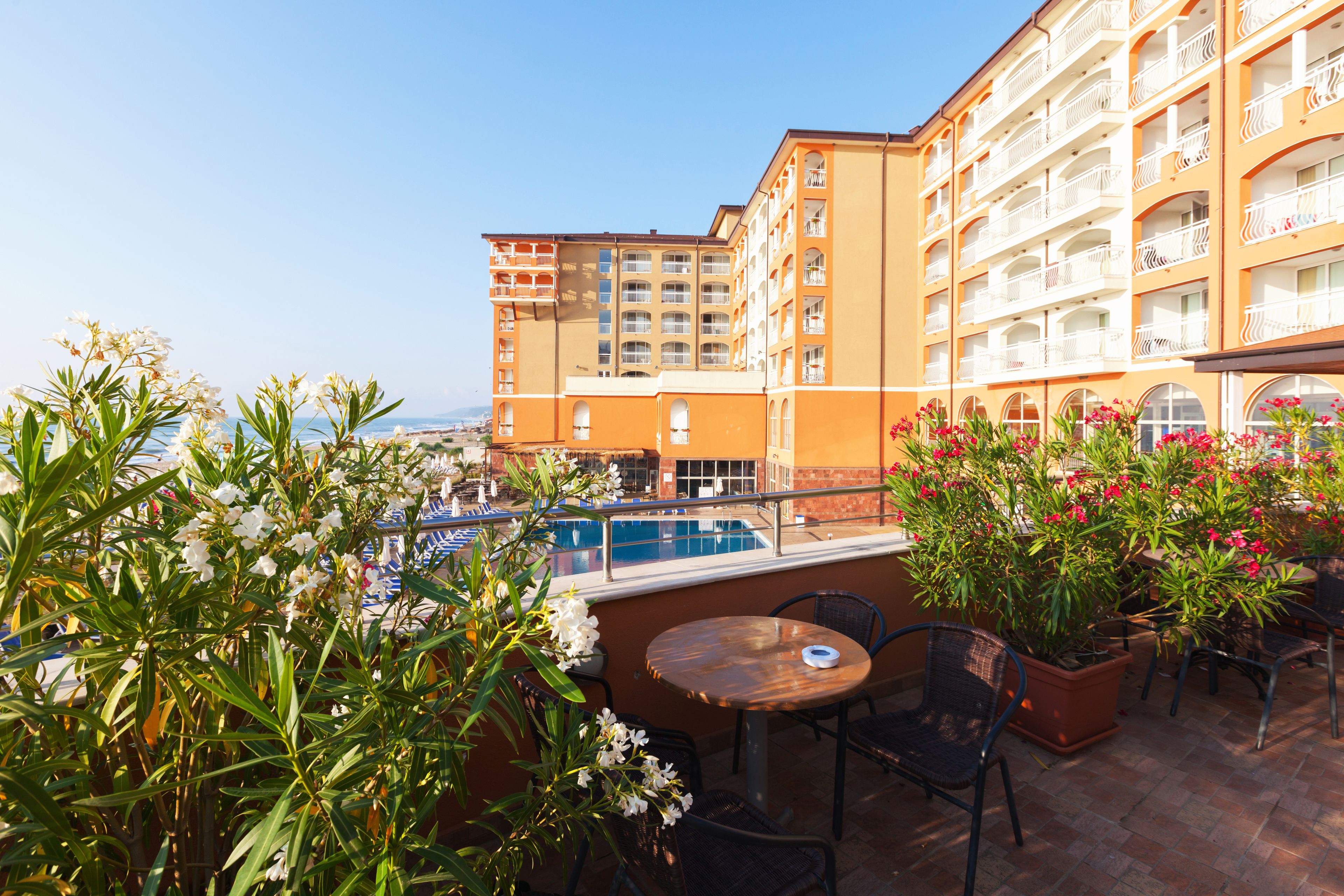 Un balcón de hotel con piscina, mobiliario exterior y vistas a la ciudad.