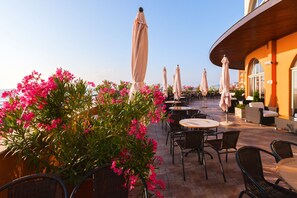 An outdoor seating area with tables and chairs, surrounded by potted plants and umbrellas. - Sol Luna Bay Resort (Byala)