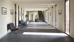 A modern hallway with a staircase, framed pictures on the walls, and a seating area with a bench and a chair.