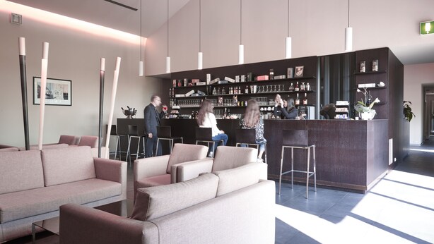 A modern lobby with sofas, a reception desk, and hanging pendant lights.