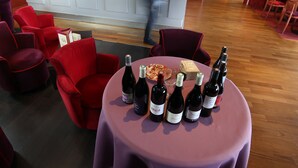 Una zona de bar con mostrador, sillas rojas y una mesa con botellas de vino.