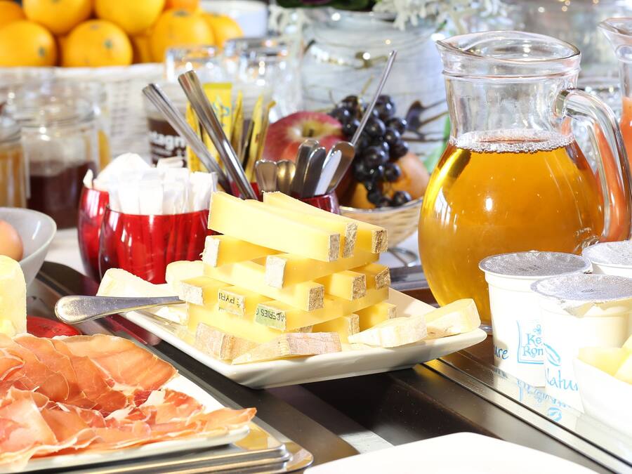 Un bufé de desayuno con diversos quesos, carnes, frutas y bebidas.