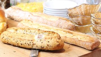 A variety of breads on a wooden surface, including a baguette and a loaf with seeds.