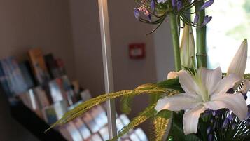Un mostrador de recepción con una lámpara, una planta en maceta con flores y un cartel que dice 'RECEPTION'.