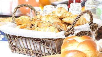 A wicker basket filled with assorted pastries, including croissants and bread rolls.
