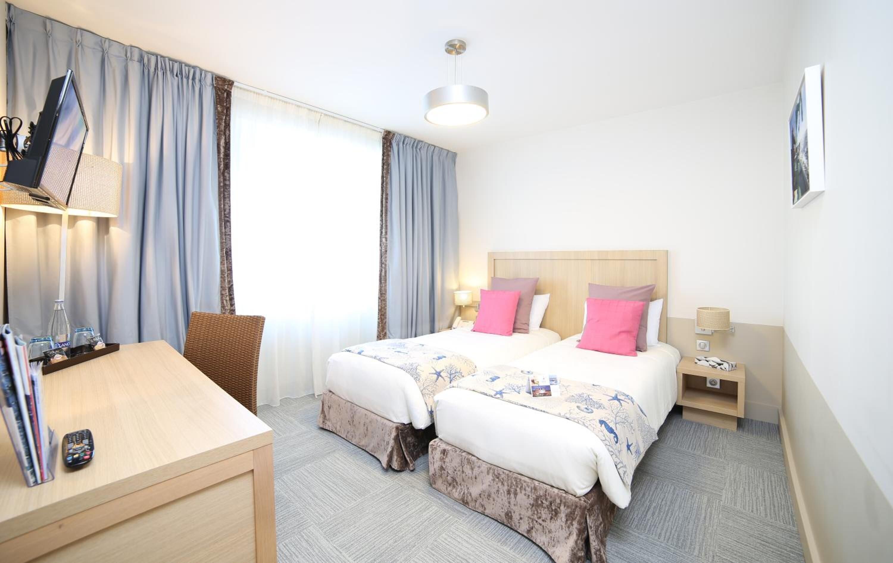 Habitación de hotel con dos camas, un escritorio y una silla.
