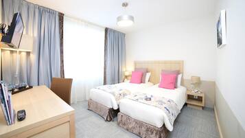 Habitación de hotel con dos camas, un escritorio y una silla.