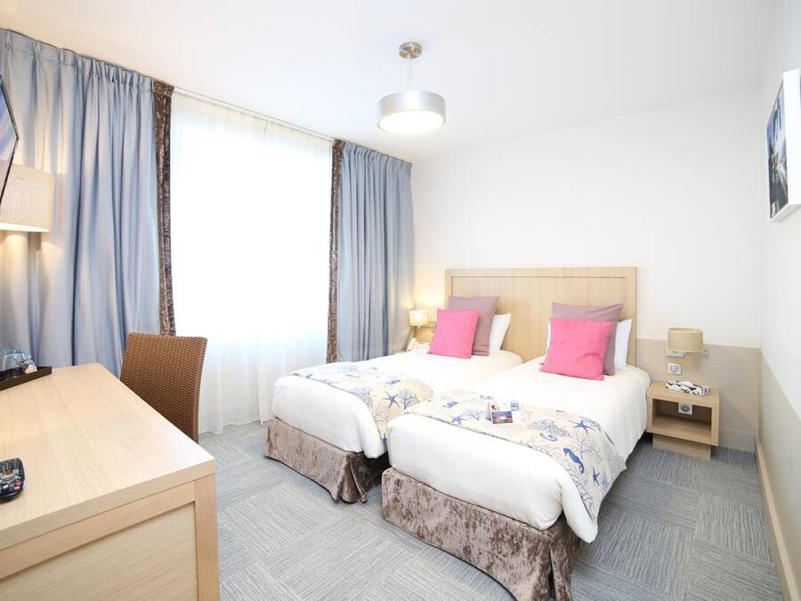 Habitación de hotel con dos camas, un escritorio y una silla.