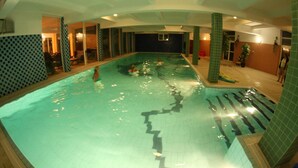 An indoor swimming pool with clear water, tiled walls, and a few people swimming. - Hotel Daisy Superior (Kraków)