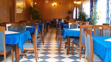 Un comedor con paredes de madera, manteles azules y suelo a cuadros.