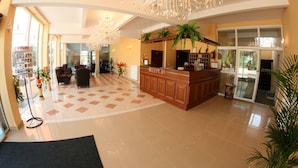 A spacious lobby with a reception desk, large chandeliers, and a check-in counter. - Hotel Daisy Superior (Kraków)