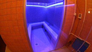 A small, enclosed room with a bench and a tiled floor, illuminated by blue lighting. - Hotel Daisy Superior (Kraków)