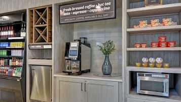 A coffee station with a coffee machine, a selection of beverages, and a sign indicating specialty coffee availability.