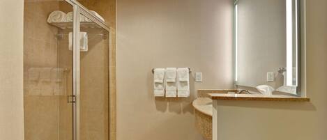 A modern bathroom with a glass shower enclosure, a sink with a mirror, and a towel rack.
