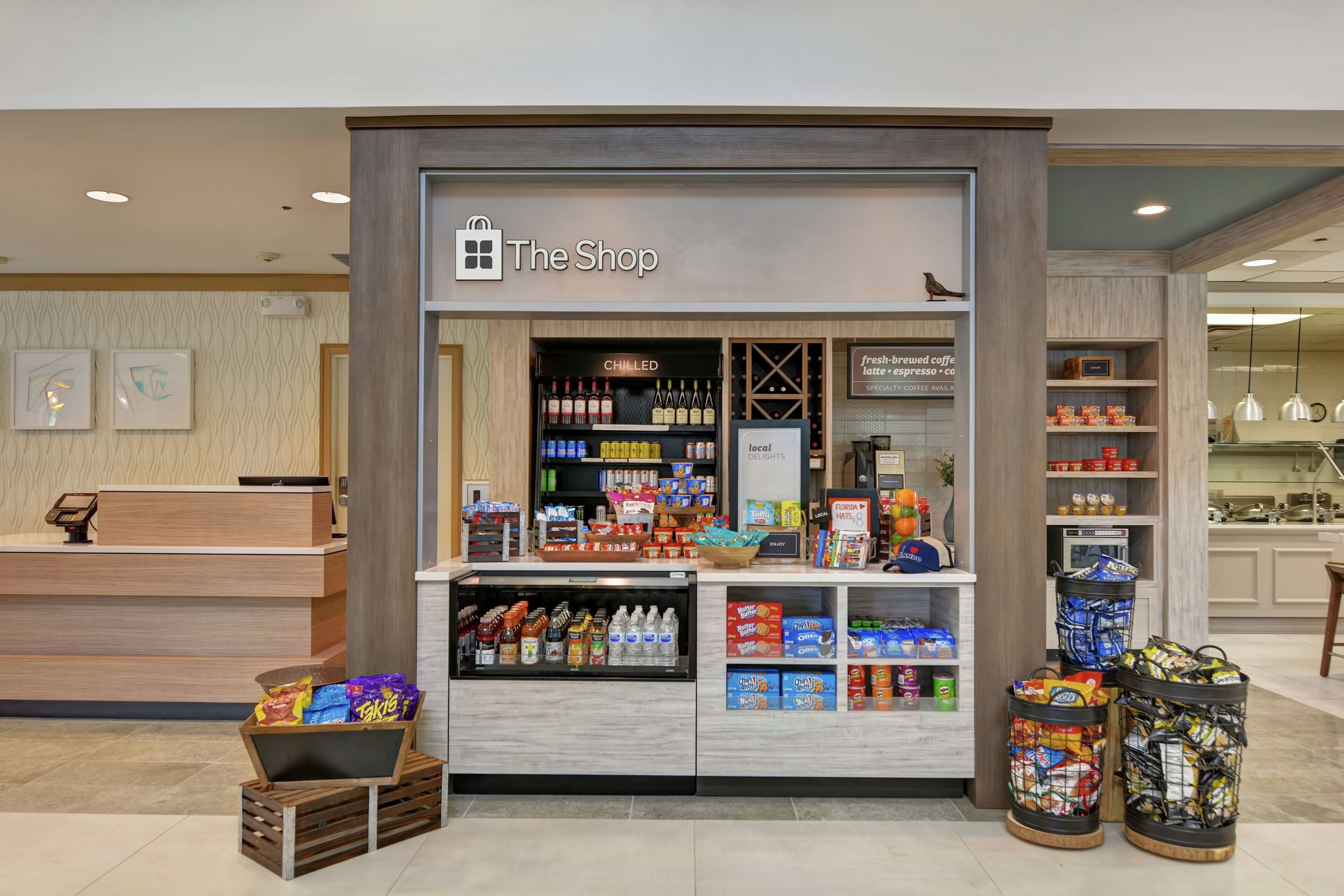 Una botiga anomenada 'The Shop' amb una secció refrigerada, estanteries amb llaminatures i una taquilla.