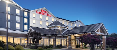 Un hotel Hilton Garden Inn con diseño moderno, que cuenta con una entrada destacada y una fachada bien iluminada.